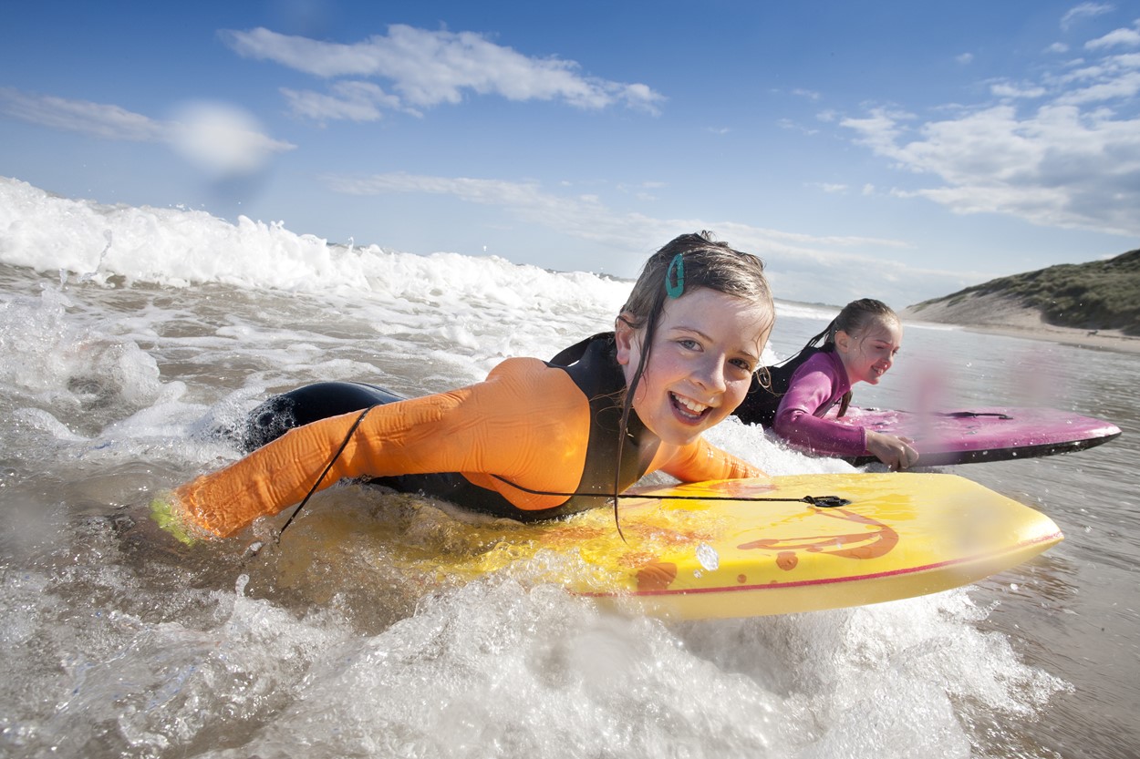 Girls riding body-boards at the beach