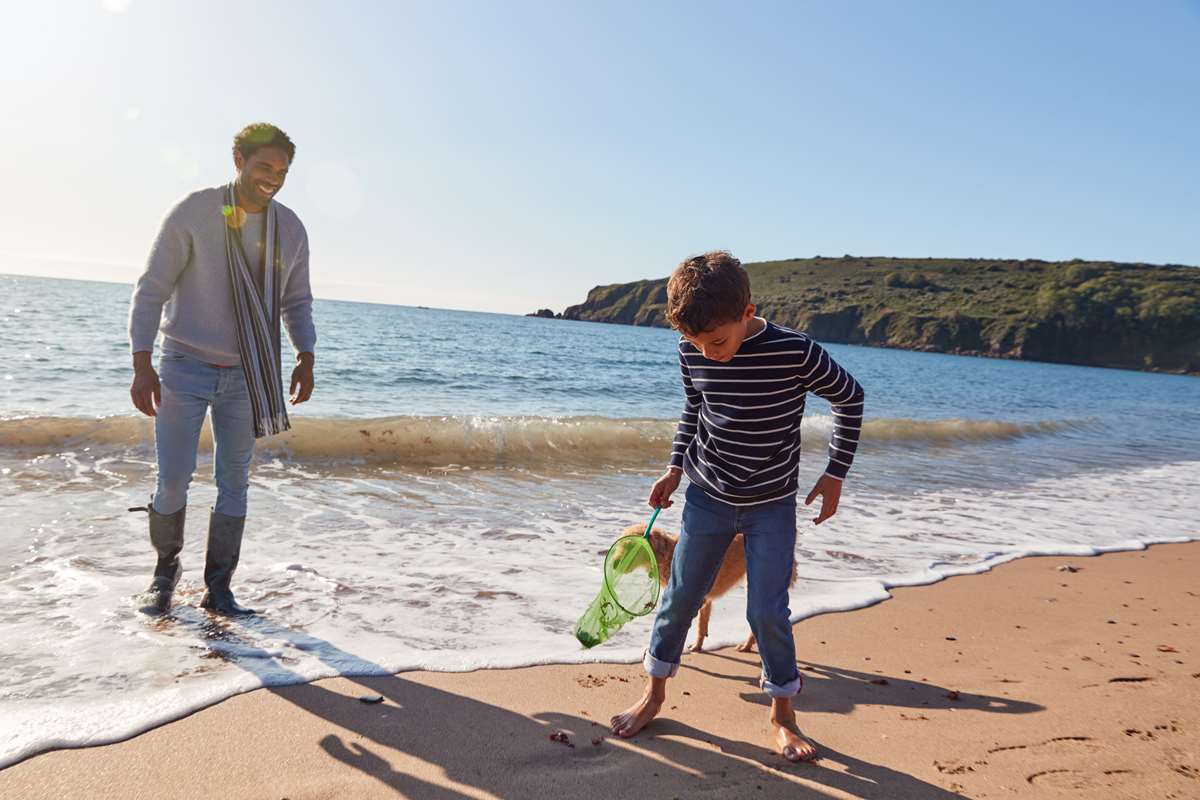 Father and son walking dog on Pembrokeshire beach
